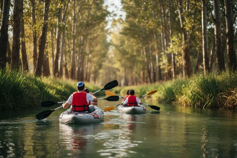 Family from behind in two inflatable kayaks on a narrow tree-lined river, father in a kippah, children in red life jackets
